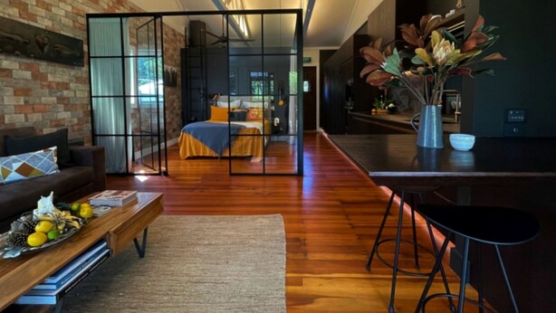 A modern living room with a sofa, coffee table, and a dining area with a bar stool.