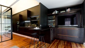 A modern kitchen with dark cabinetry, a central island, bar stools, and a wine rack.