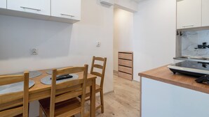A modern kitchen with white cabinets, a wooden dining table with chairs, and a built-in stove.
