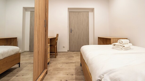 A bedroom with two wooden beds, a desk, and a door.