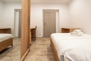 A bedroom with two wooden beds, a desk, and a door. - Zawodzie 3-Bedroom Apartment (Katowice)