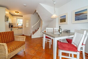 Ein gemütlicher Essbereich mit Tisch und Stühlen, im Hintergrund eine Küche und eine Treppe, die nach oben führt.