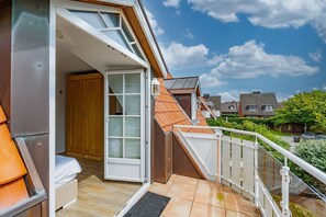 Eine moderne Wohnung mit Balkon, einer Holztür und Blick auf Nachbarhäuser.