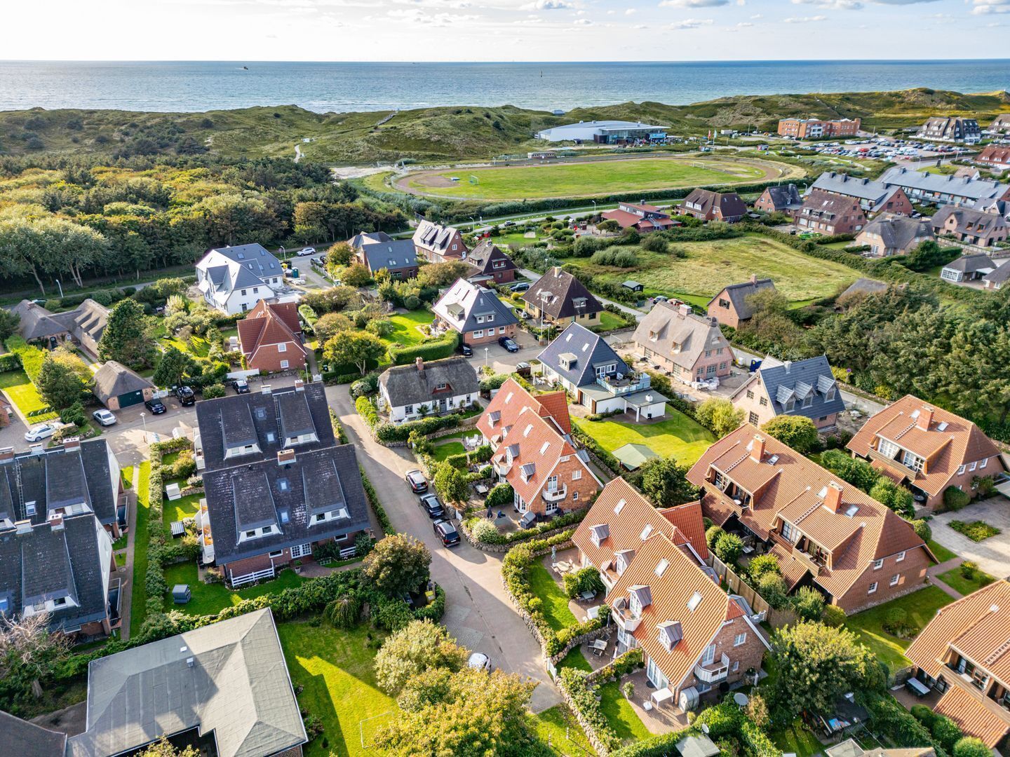 Un quartier résidentiel avec des maisons, un grand immeuble et une vue sur la mer.