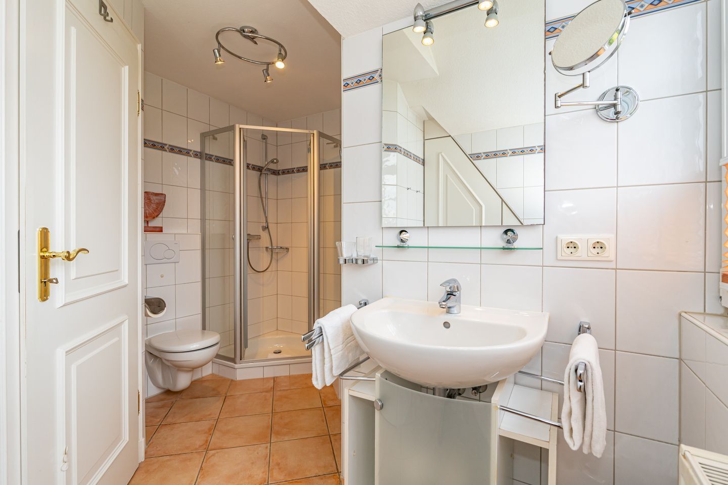 Une salle de bain moderne avec une douche à parois de verre, un lavabo blanc et des toilettes.