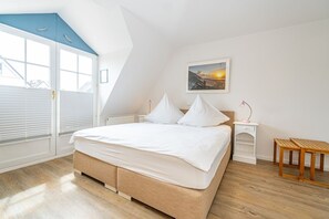 Ein Schlafzimmer mit einem großen Bett, einem Nachttisch, einem kleinen Tisch und einem Fenster mit Jalousien.