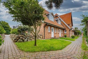 Une maison en briques avec un toit en pente, un mur en pierre et un chemin pavé.