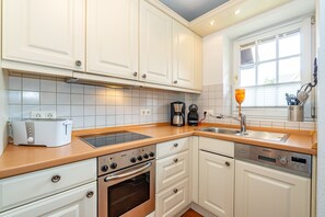 A modern kitchen with white cabinets, a Bosch oven, a Siemens dishwasher, a coffee maker, and a toaster. - Meeresleuchten - Ab 2025 bei uns im Angebot, für Max. 4 Personen (Sylt)