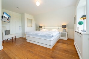 Ein Schlafzimmer mit einem großen Bett, Nachttischen, einer Bank, einem Spiegel und einer Heizung.