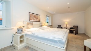 A modern bedroom with a large bed, bedside tables, a chair, and a desk.