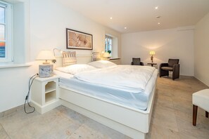 A modern bedroom with a large bed, bedside tables, a chair, and a desk.