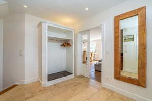 Ein modernes Interieur mit begehbarem Kleiderschrank, großem Spiegel und Blick in einen Essbereich.