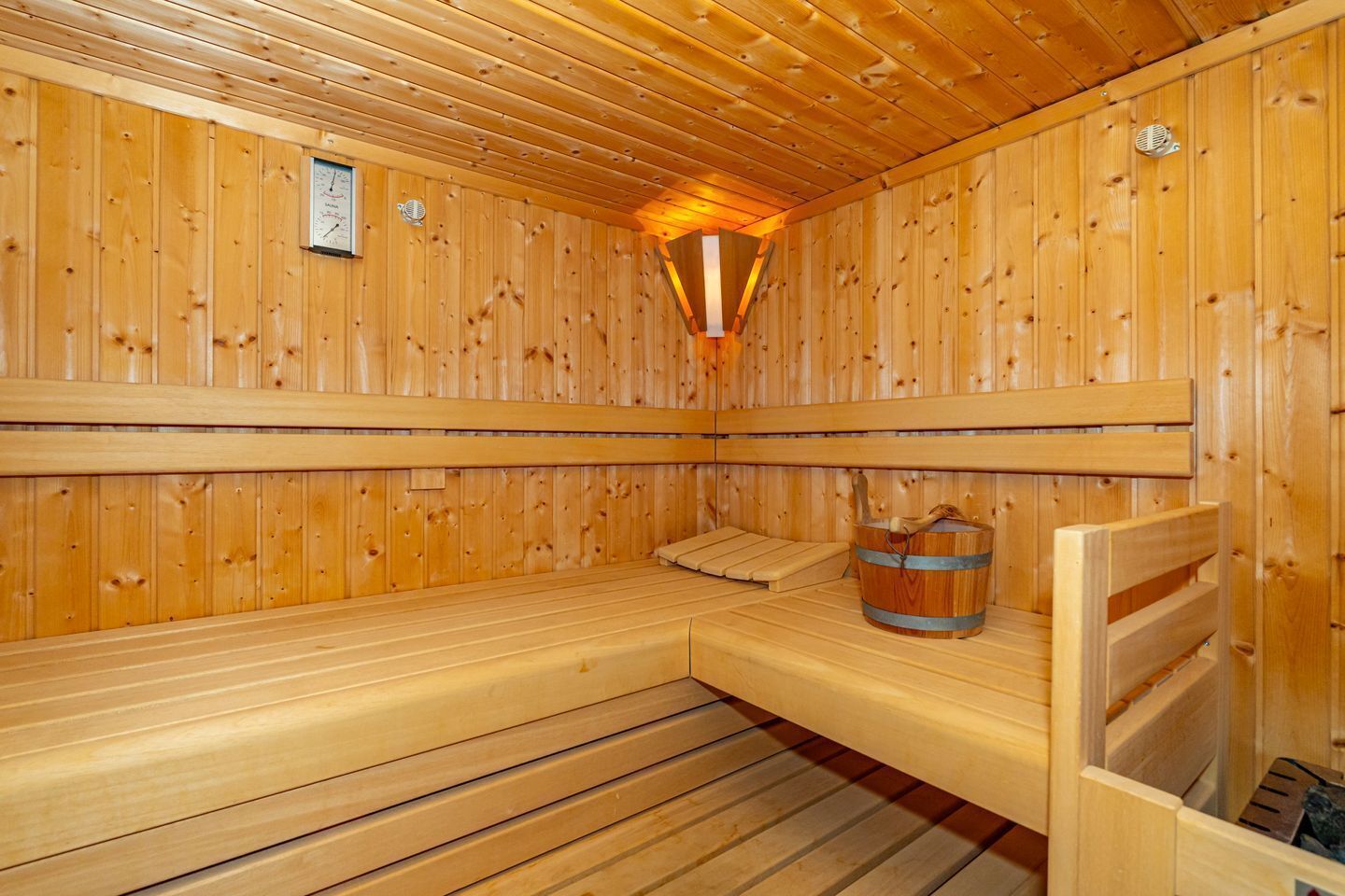 Una sauna in legno con panche e un catino.