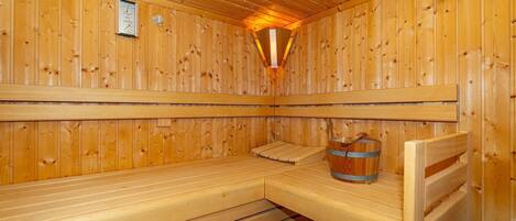 A wooden sauna with benches and a bucket.