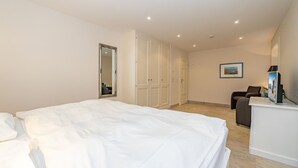 Hotellihuone, jossa on suuri sänky, työpöytä, tuoli ja peili.