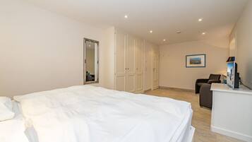 Ein Hotelzimmer mit einem großen Bett, einem Schreibtisch, einem Sessel und einem Spiegel.