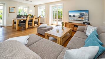 Ein geräumiges Wohnzimmer mit großem Sofa, Couchtisch und Essbereich mit Tisch und Stühlen.