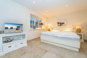 Une chambre à coucher avec un lit, une télévision, une fenêtre et une table de chevet.