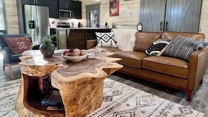 Ein gemütliches Wohnzimmer mit einem braunen Ledersofa, einem Holztisch und einem gemusterten Teppich.