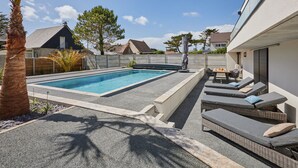 A swimming pool with a sun lounger area and a palm tree. - Denneweiller by Interhome (Denneville)