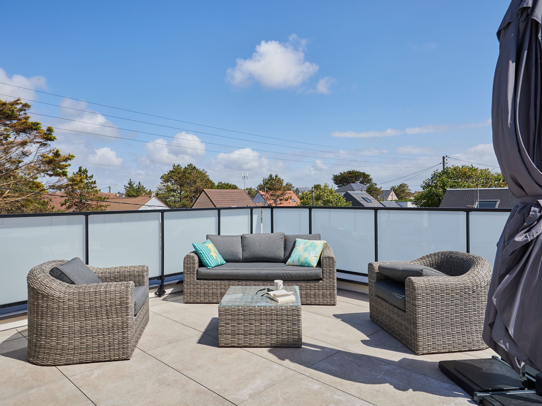 A rooftop patio with wicker furniture, including sofas and chairs, and a covered area.