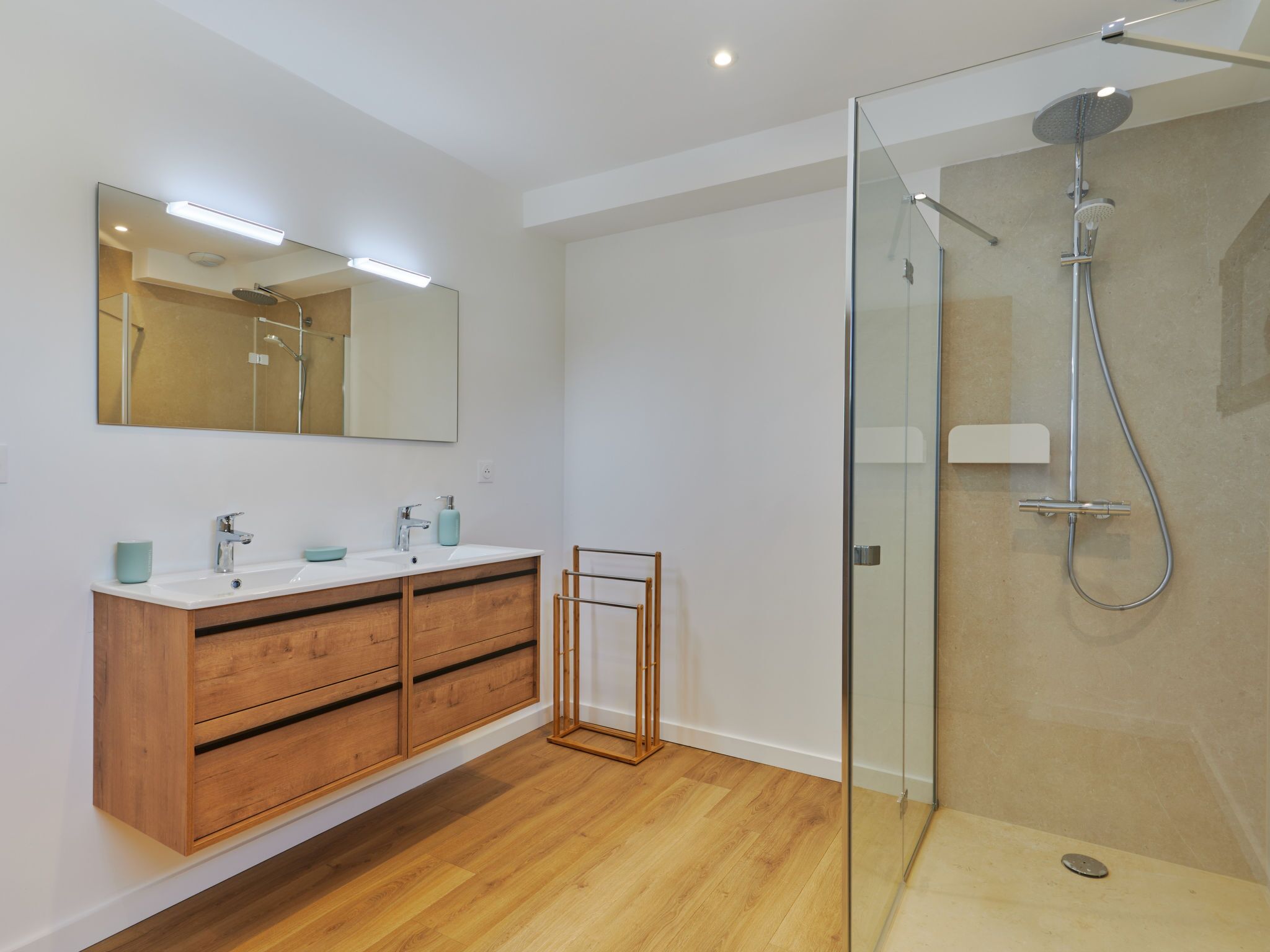 A modern bathroom with a glass-enclosed shower, wooden vanity, and a large mirror.