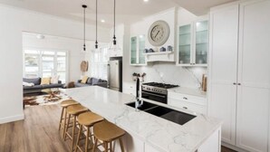 A modern kitchen with a large island, white cabinetry, and pendant lighting.