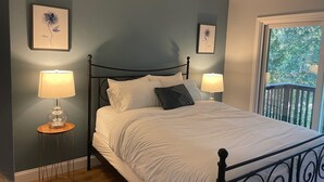 Un llit ben arropat amb roba de llit blanca, dues làmpades de nit i quadres florals a les parets.