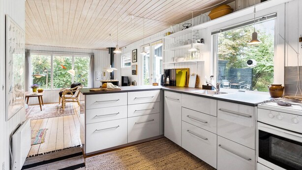 Een moderne keuken met witte kastjes, een groot raam en een inbouwoven.