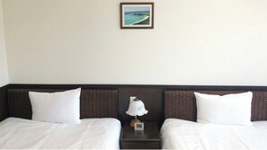 Une chambre d’hôtel avec deux lits, une table de chevet avec une lampe et un tableau encadré au mur.