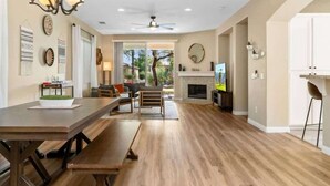 A spacious kitchen with wooden flooring, a dining area with a long table, and a fireplace. - Lake View 3BR | Resort Pools at Indian Palms (Indio)