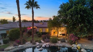 A residential property with a swimming pool, palm trees, and a well-maintained garden. - Lake View 3BR | Resort Pools at Indian Palms (Indio)