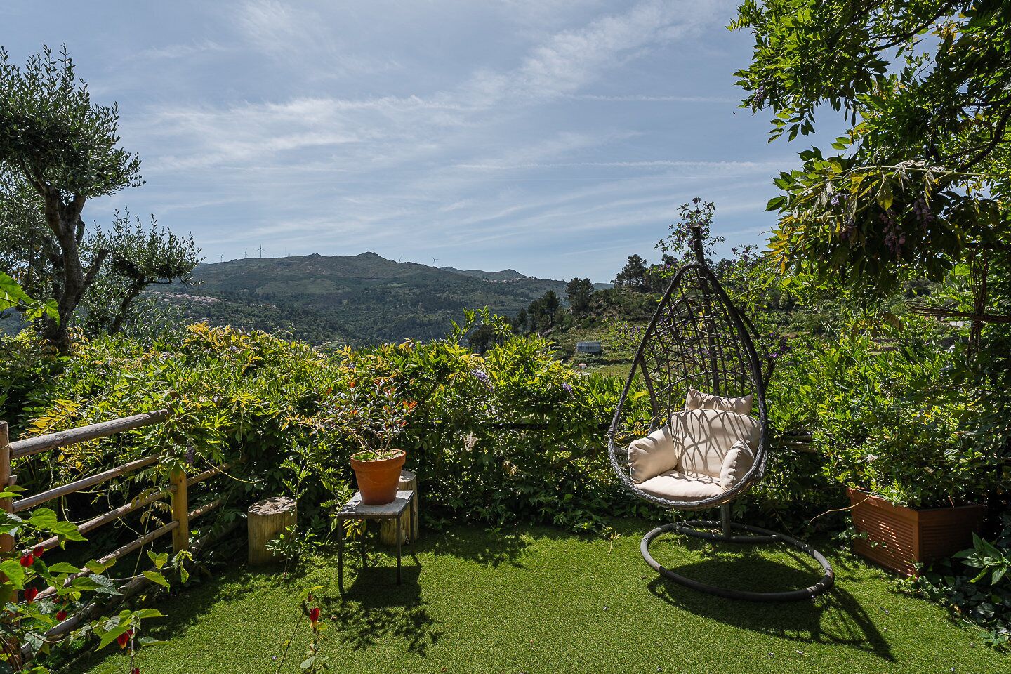 A garden with a hanging chair, a small table, and a potted plant.