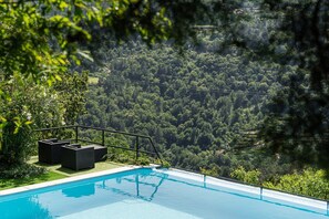Une piscine avec vue sur une colline boisée.