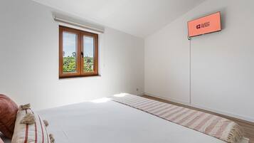 Habitación de hotel con cama, ventana con vistas, televisor de pantalla plana y alfombra.