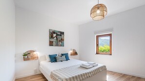 A bedroom with a bed, a window with a view, a hanging light fixture, and a wall-mounted artwork. - Casa Museu da Geada - Rural Hotel (Cinfães)