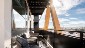 A balcony with wicker furniture, a view of the city, and a large wooden beam structure. - Serenity in Style | Espadin LoHi (Denver)