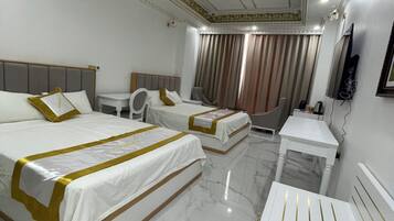 A hotel room with two beds, a desk, a chair, a TV, and a bathroom.