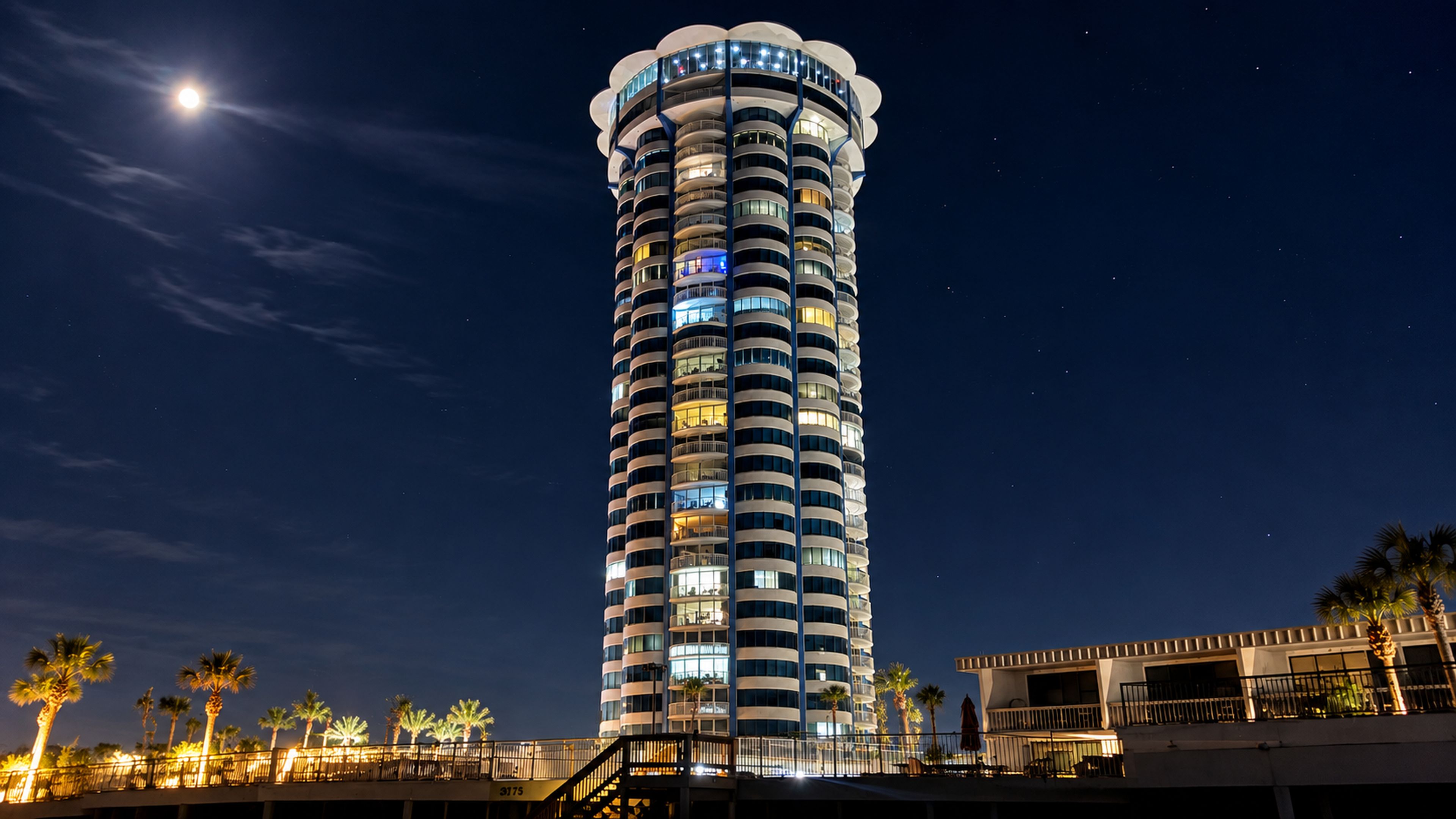 Un hotel alto y cilíndrico con múltiples balcones y una fachada iluminada.