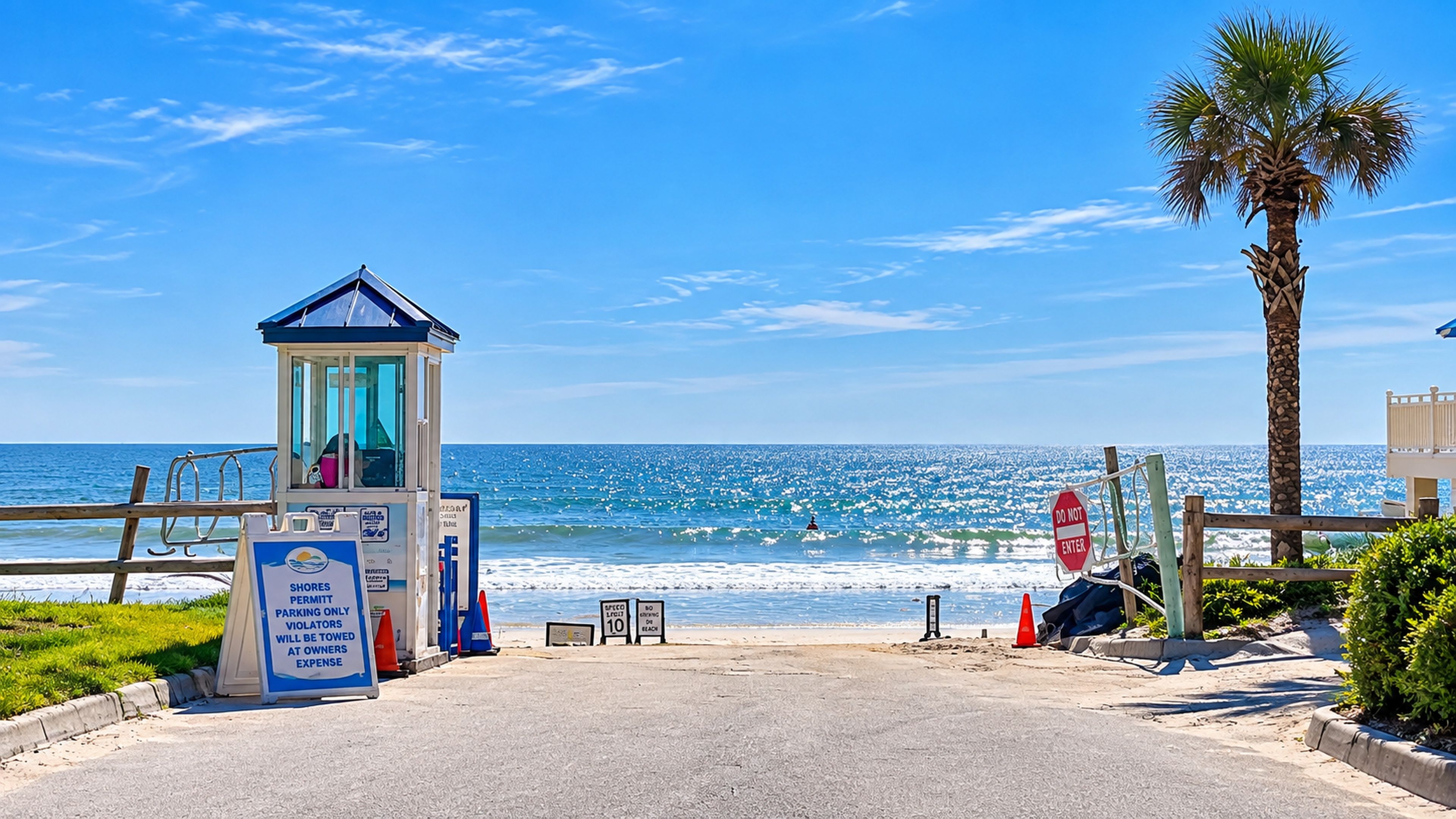 Una entrada a la playa con una torre de salvavidas, un letrero de 'NO PASAR' y una palmera.