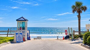A beach entrance with a lifeguard tower, a 'DO NOT ENTER' sign, and a palm tree. - 2BR/2BA • Beachfront • Hot Tub • Pool • Ball Courts • Gym • Fire Pit • 8NE (Daytona Beach)