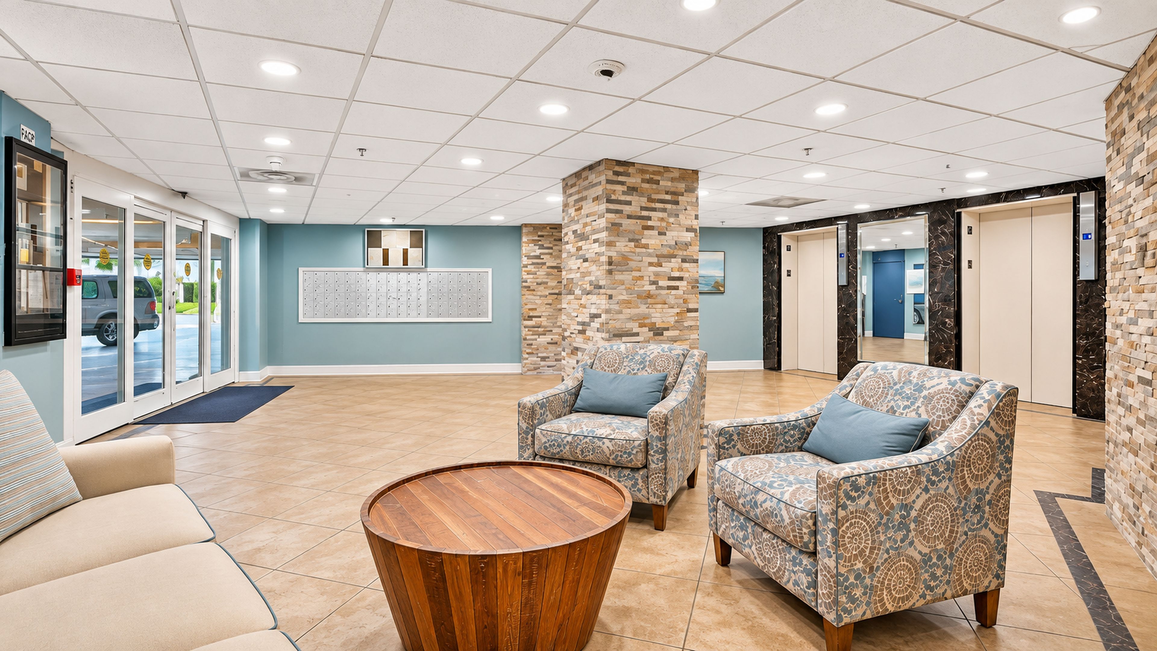 A lobby with two patterned armchairs, a wooden coffee table, and a reception desk.