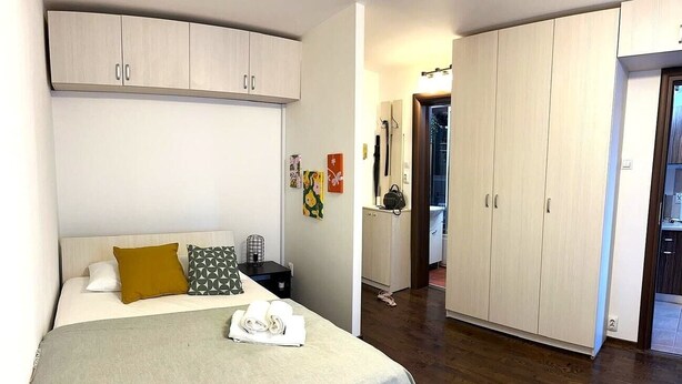 Une chambre à coucher comprenant un lit, une table de chevet, une armoire et un couloir menant à une autre pièce.