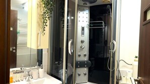 Une salle de bain moderne avec une douche à parois de verre, un lavabo équipé de produits de toilette et un miroir.