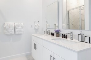 A modern bathroom with white cabinetry, a large mirror, and a countertop with toiletries. - Enchanted Grove by Avantstay 30mins to Disney Private Pool (Davenport)