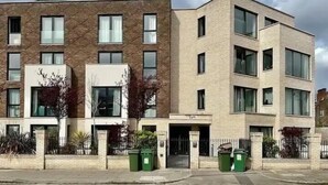 A multi-story residential building with a brick facade, large windows, and a flat roof. - Bright 2BR - 2Bath Apt with Balcony | Kentish Town (Greater London)