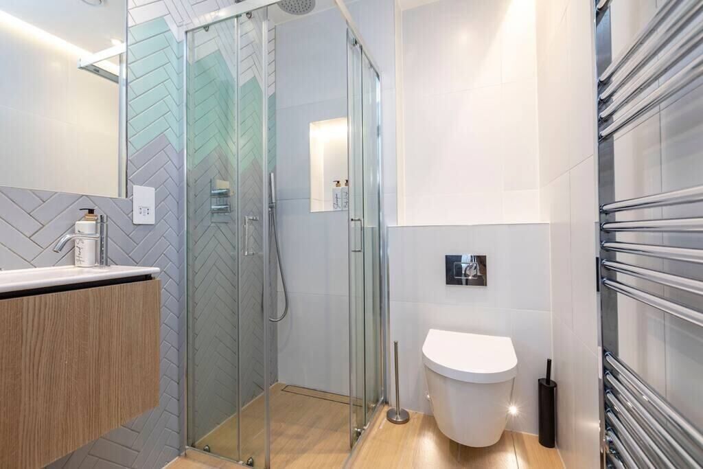 A modern bathroom with a glass shower enclosure, a white toilet, and a wooden vanity.
