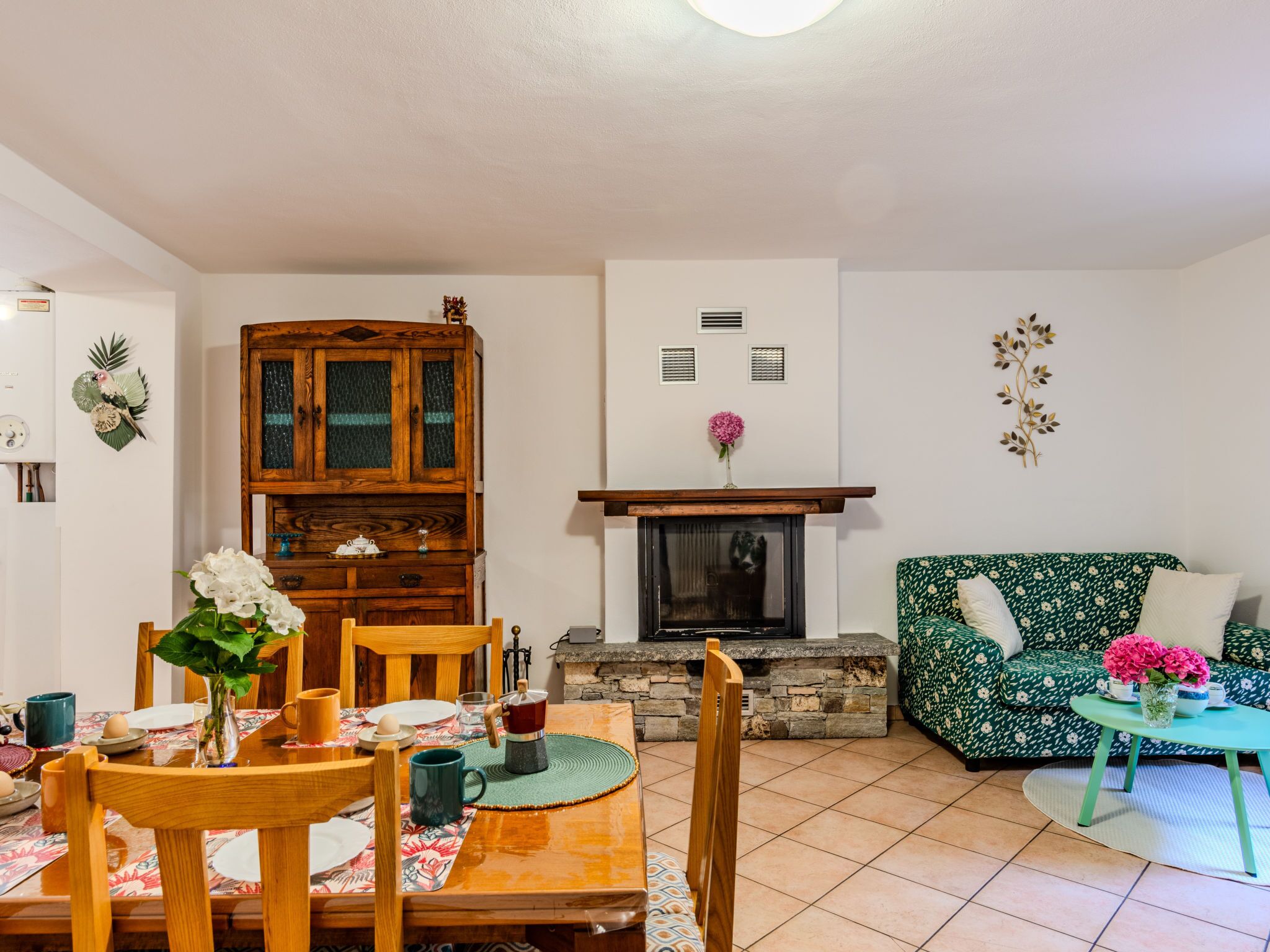 Una sala de estar acogedora con chimenea, una mesa de comedor con sillas y un sofá estampado.