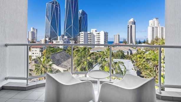 A balcony with a view of a cityscape, including modern buildings and palm trees. - Surfers Paradise Studio with Ocean Views (Surfers Paradise)