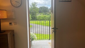 A door leading to a garden with a view of a road and greenery. - Studio-King Bed-Wye Valley Views (Bettws Newydd, Usk)